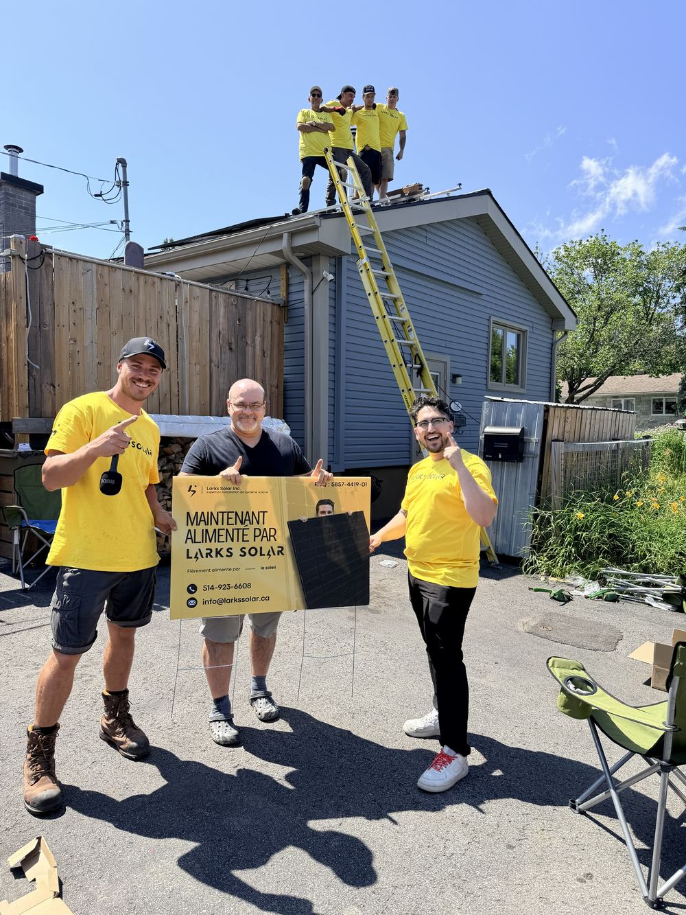 L'équipe Larks Solar et un client de Laval devant sa maison, le jour de l'installation, avec la pancarte « Maintenant alimenté par Larks Solar »