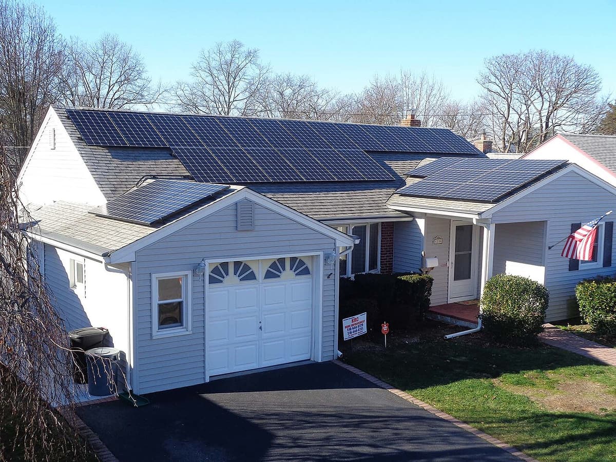 Bungalow avec garage et panneaux solaires noirs sur le toit