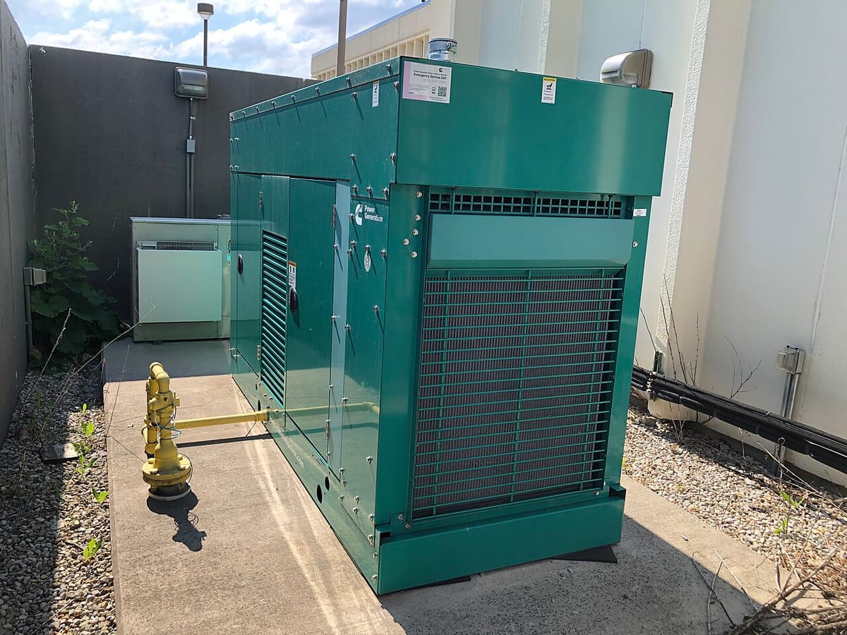 Génératrice fixe dans un caisson vert à l'extérieur d'un bâtiment