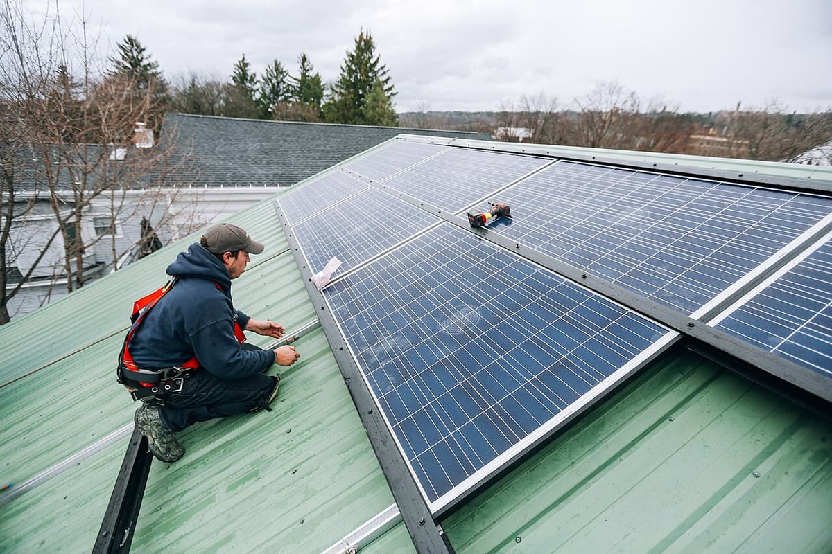 Installateur agenouillé qui fixe un panneau sur un toit en tôle
