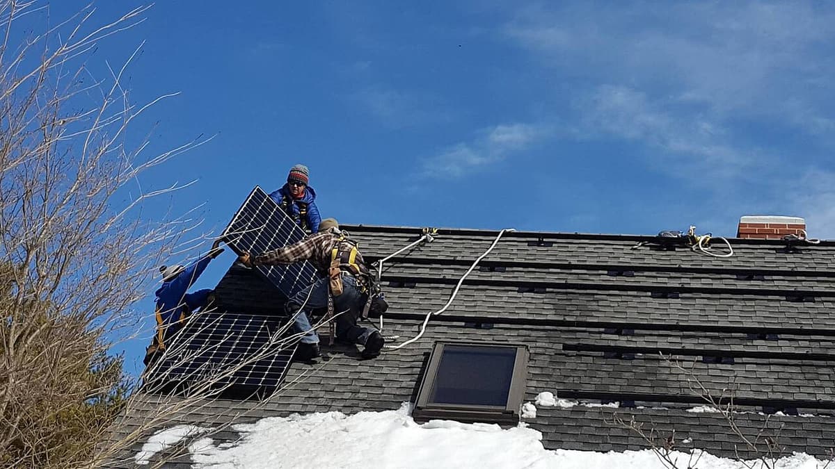Installateurs sur un toit en bardeaux par temps froid, ciel bleu