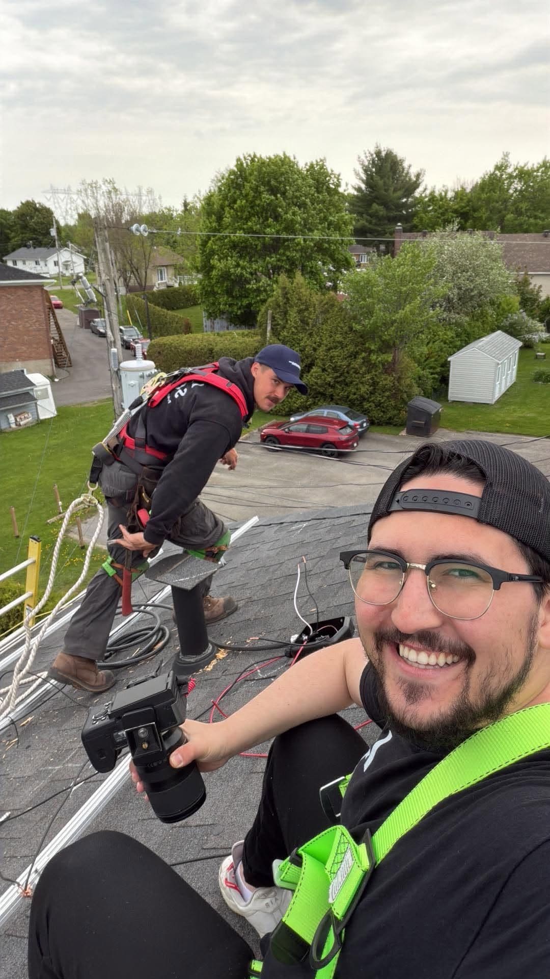 Deux membres de l'équipe Larks Solar sur un toit en bardeaux, harnais attachés, pendant une installation