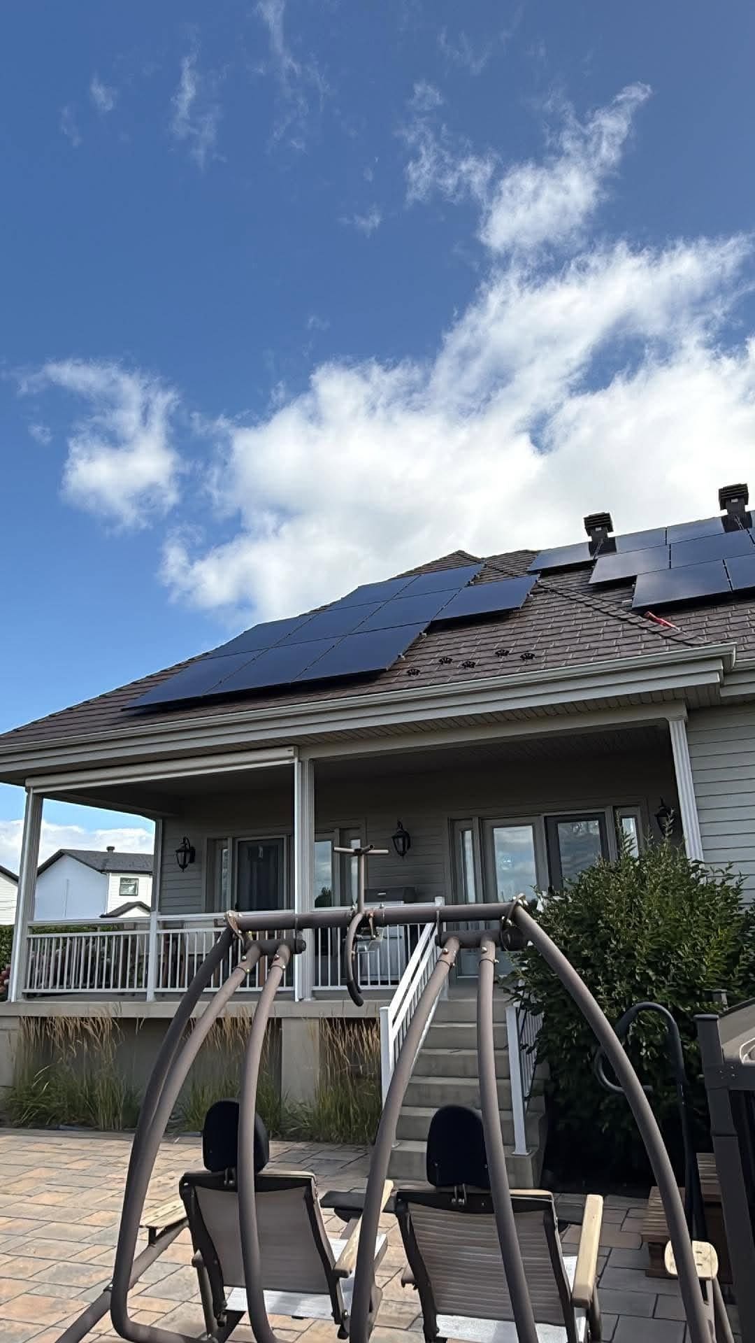 Maison au toit d'acier brun couvert de panneaux solaires noirs, vue de la cour arrière