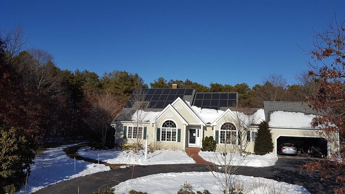 Maison unifamiliale avec panneaux solaires sur le toit, neige au sol