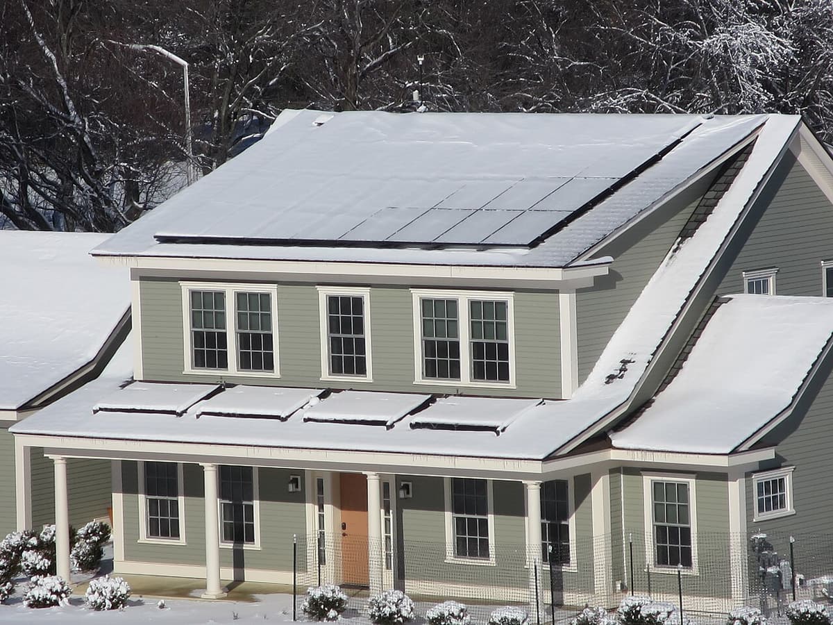 Maison de deux étages avec panneaux solaires couverts de neige