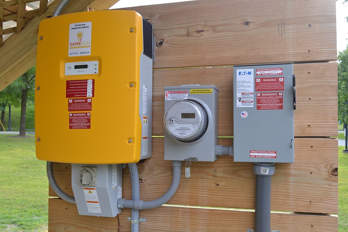 Onduleur, compteur et sectionneur fixés sur un mur de bois
