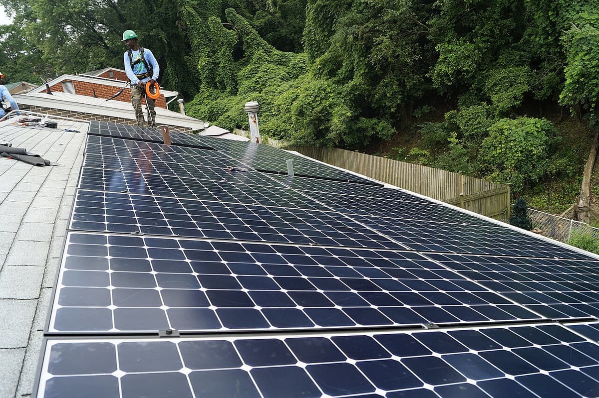 Longues rangées de panneaux solaires en cours d'installation sur un toit