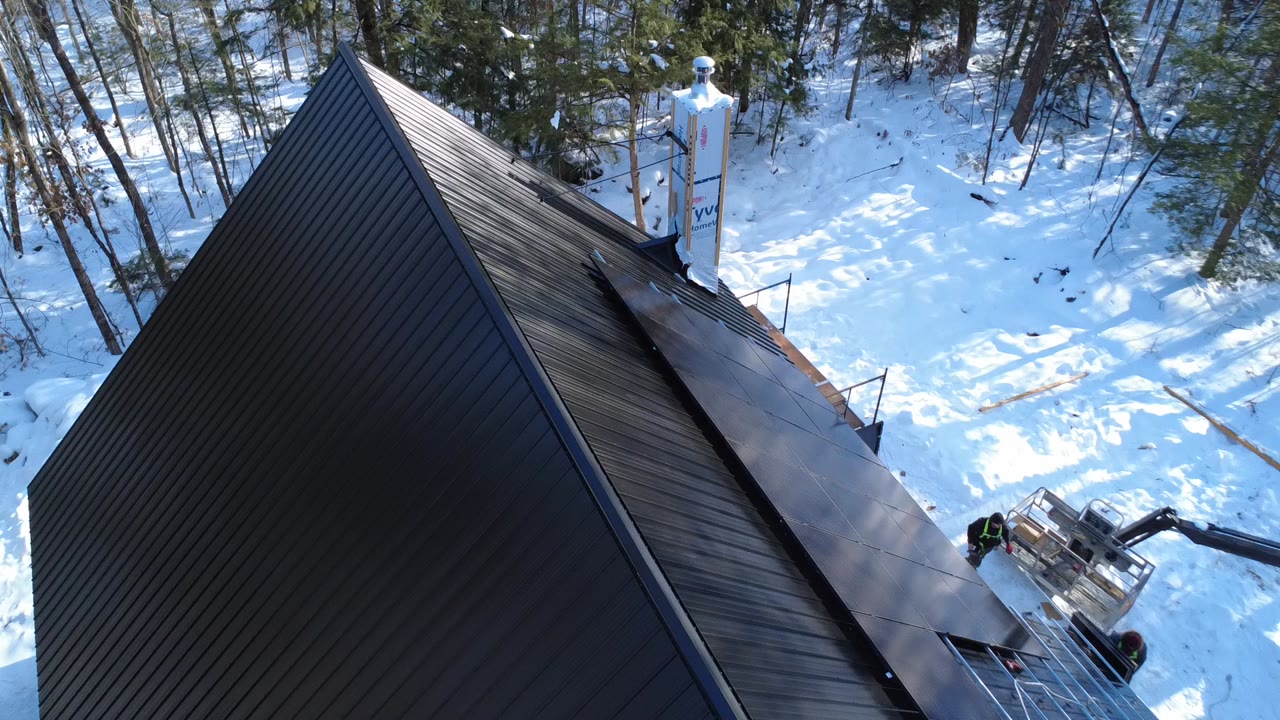 Vue de drone d'une installation hivernale de panneaux solaires par Larks Solar à Saint-Calixte, sur un toit d'acier noir